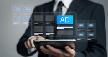 A man in a suit holds a tablet displaying ad words for an advertising campaign.